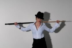 Shooting d'un modèle par un photographe tenant une queue de billard, avec forte ombre